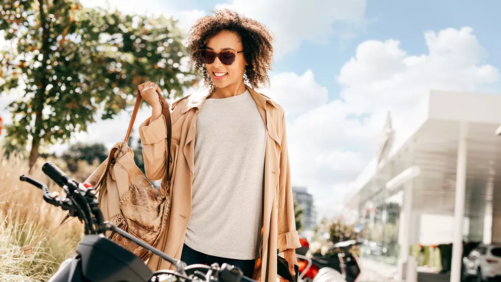 Mujer con cabello rizado en una motocicleta, con gafas de sol.